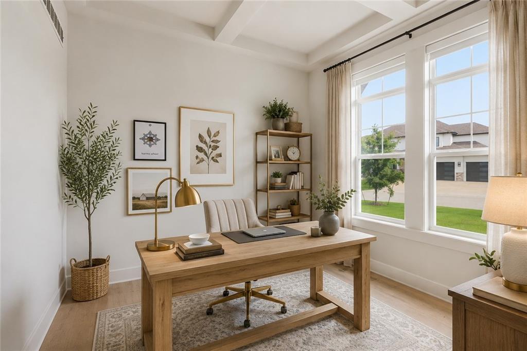 Main-level private office with a beamed ceiling, a light wood desk and brass lamp, open shelving, and two large windows overlooking the street